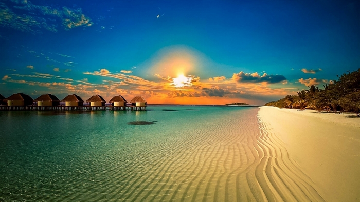 Overwater bungalows at sunset on a tropical beach