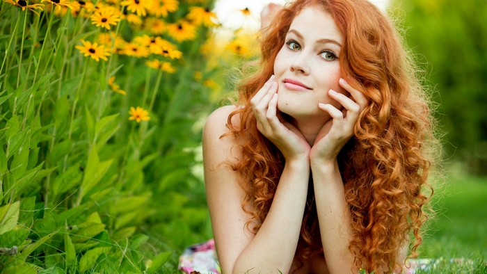 Redhead woman lying in grass with flowers