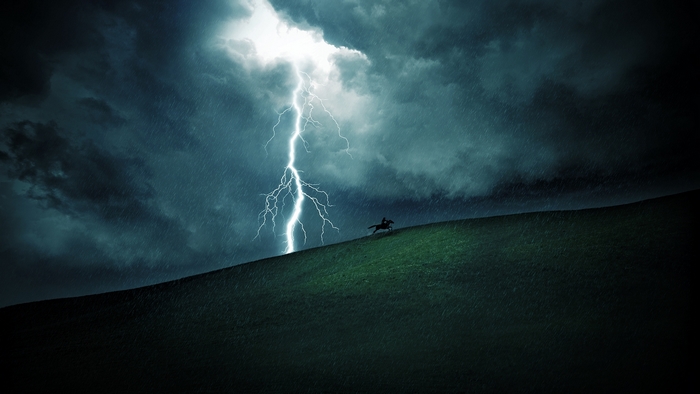 Horse rider on a hill during a lightning storm