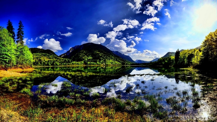 Mountain lake reflection with trees and clouds