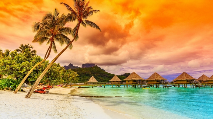 Tropical beach with overwater bungalows at sunset