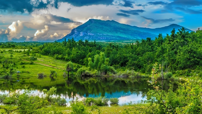 Mountain landscape with a pond and green fields