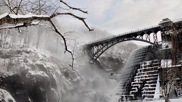 Snowy bridge over a waterfall and dam