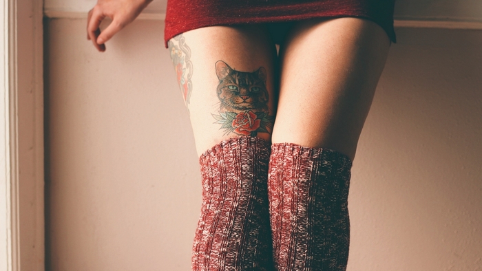 Woman with cat tattoo on thigh wearing thigh-high socks