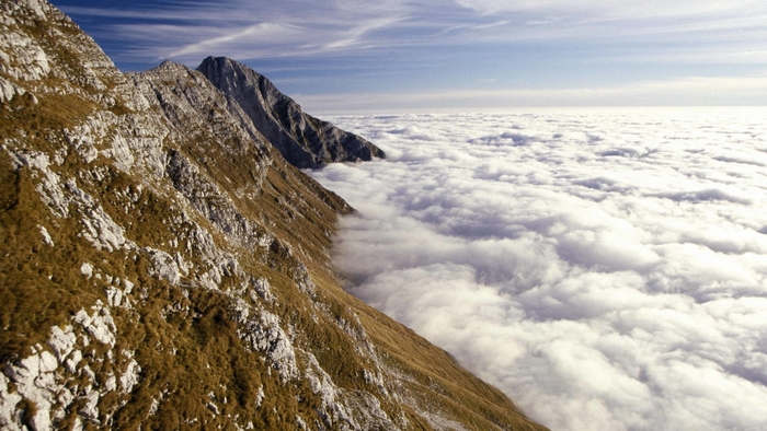 Mountain peak above clouds with blue sky