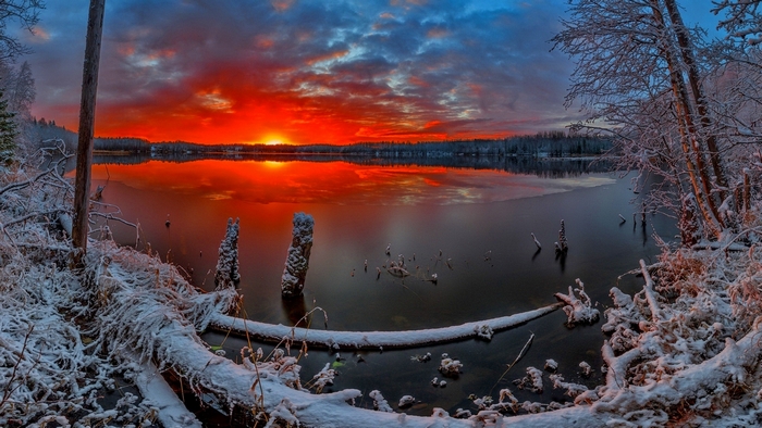Winter sunset over a snow-covered lake with reflections