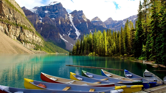 Canoes on a turquoise lake with mountains and forest