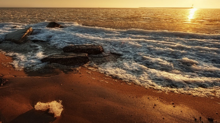 Ocean waves crashing on a beach at sunset