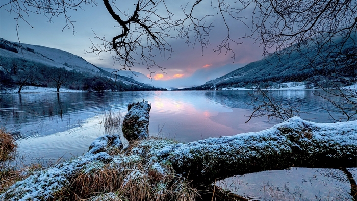 Winter sunset over a snowy lake with mountains and trees