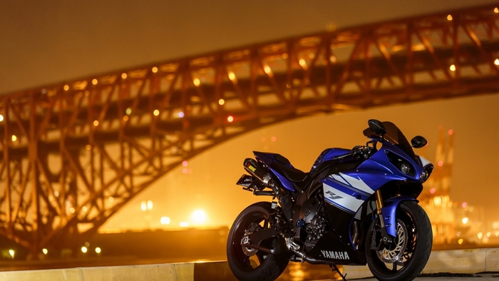 Blue Yamaha R1 motorcycle parked near a bridge at night