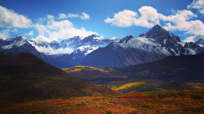 Snow-capped mountains under a blue sky with clouds