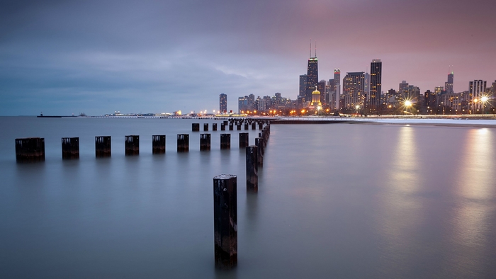 Chicago skyline with wooden posts in Lake Michigan at dusk