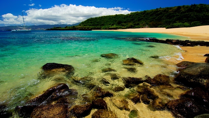 Turquoise ocean water with rocks and a sandy beach