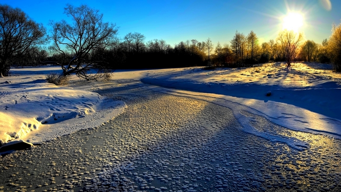 Winter landscape with frozen river and bright sunshine