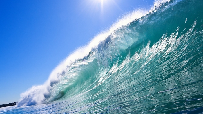 Ocean wave crashing under the sun