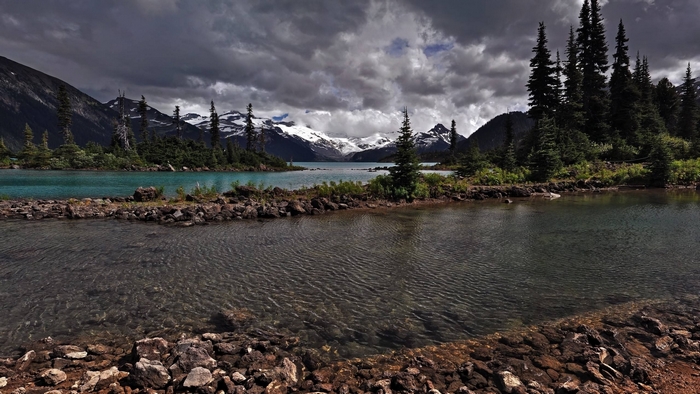 Mountain lake with snow-capped peaks and dark clouds