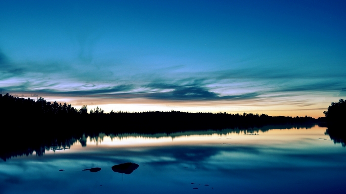 Sunset over a forest lake with reflections