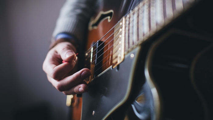 Person playing a guitar with a pick