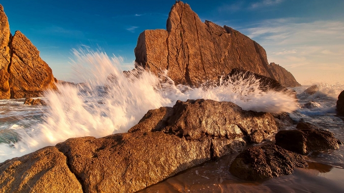 Waves crashing on rocky shore at sunset