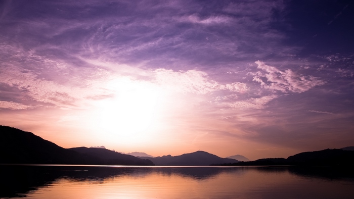 Purple sunset over a lake with mountains and reflection