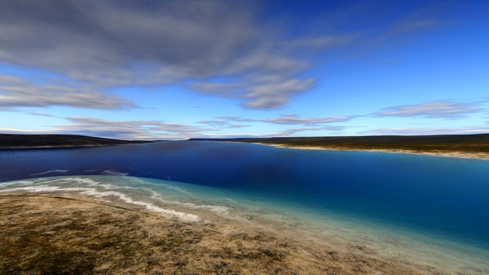 Vast blue lake with sandy shore and cloudy sky