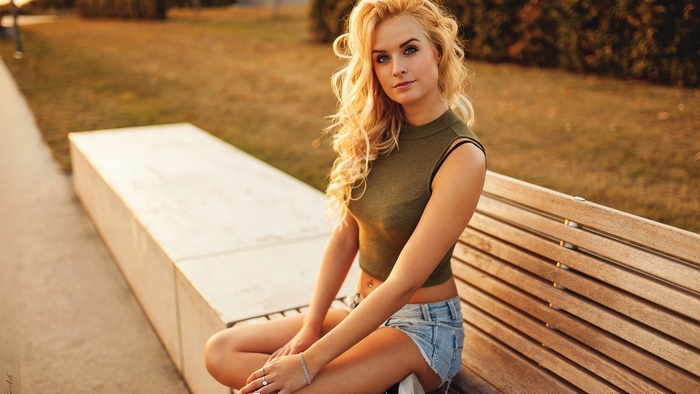 Blonde woman sitting on a park bench