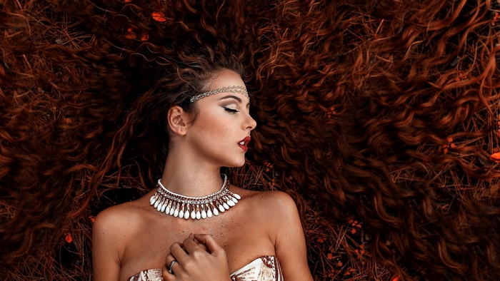 Woman with long curly red hair lying down