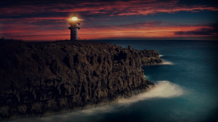 Lighthouse on a rocky cliff at sunset