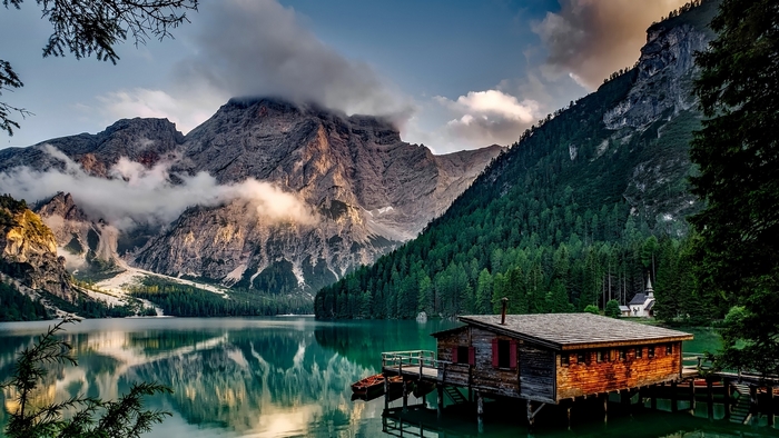Wooden boathouse on a lake with mountains and forest