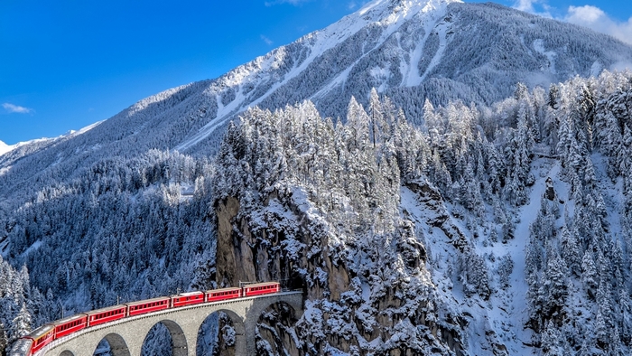Red train on a snowy viaduct in the Swiss Alps