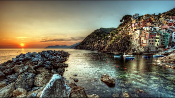 Colorful Italian village on a cliffside by the ocean at sunset