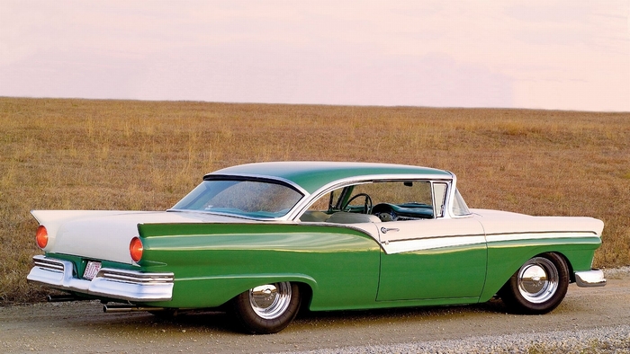 Green and white 1957 Ford Fairlane parked on a dirt road