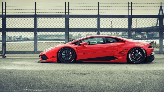 Red Lamborghini Huracan parked near a fence