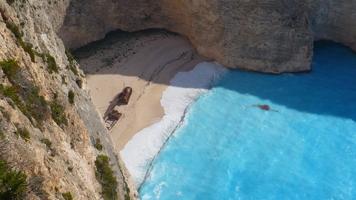 Shipwreck on a beach with cliffs and blue ocean