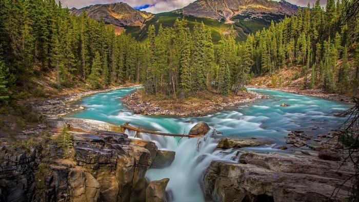 Turquoise river flowing through a forest with mountains