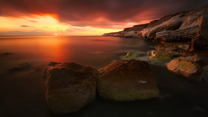 Sunset over the ocean with rocky shore