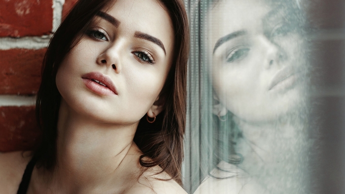 Woman posing by a brick wall and window