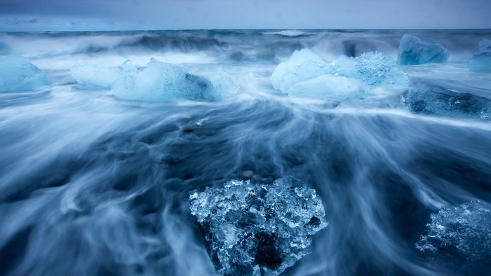 Icebergs on a black sand beach with ocean waves