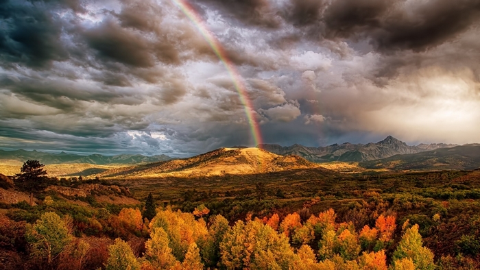 Rainbow over autumn forest and mountains