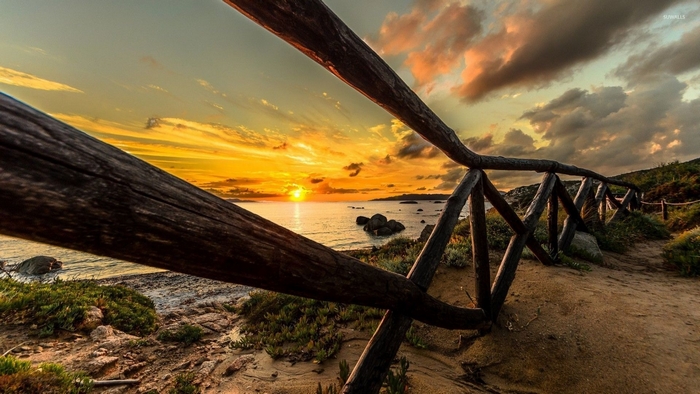 Wooden fence on a beach at sunset