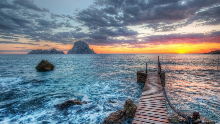 Wooden pier at sunset with islands and colorful sky