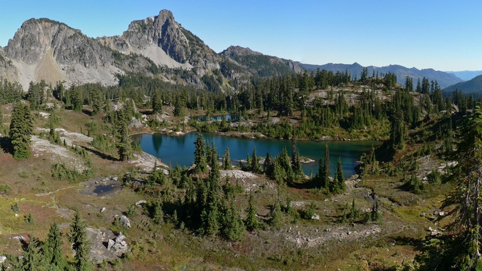 Mountain lake with pine forest and rocky peaks