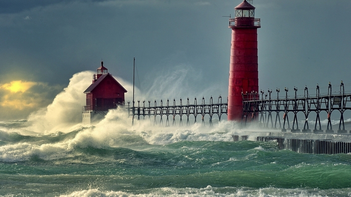 Red lighthouses on a pier during a storm with large waves