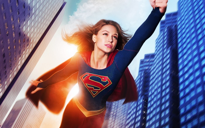 Supergirl flying between buildings