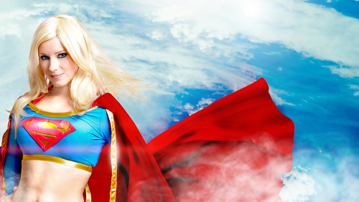 Supergirl in a blue and red costume against a cloudy sky