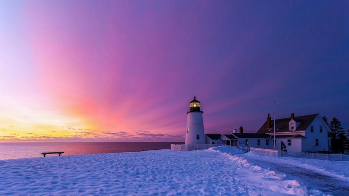 Lighthouse and house in snow at sunset