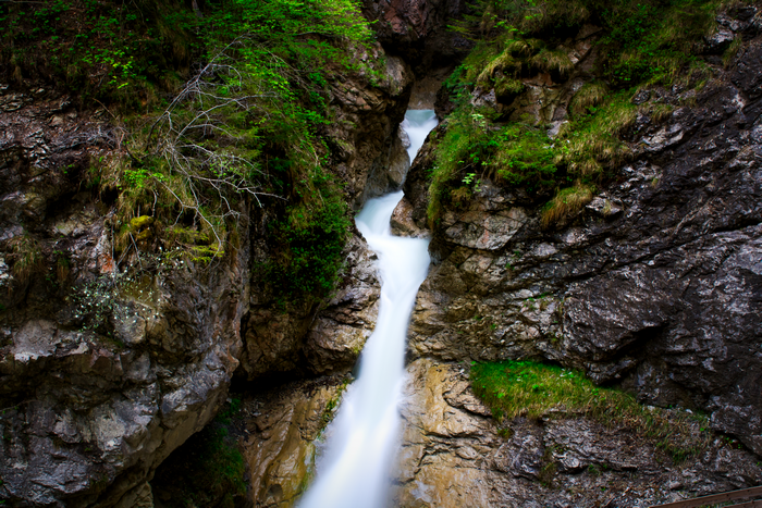 Waterfall flowing through a rocky gorge with greenery