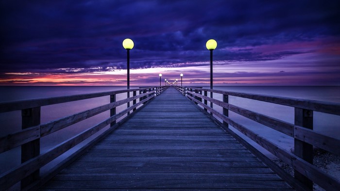 Wooden pier with lamps at sunset
