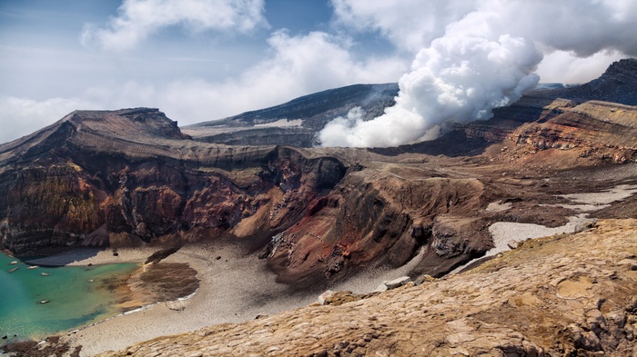 Mount Aso volcano crater with turquoise lake and steam