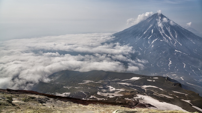 Volcano erupting above clouds